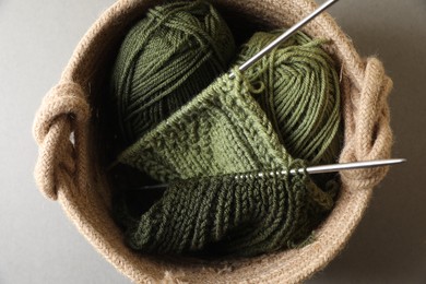 Green knitting, needles and soft yarns on light background, top view