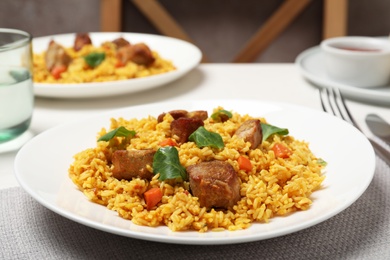 Photo of Plate of delicious rice pilaf with meat on table