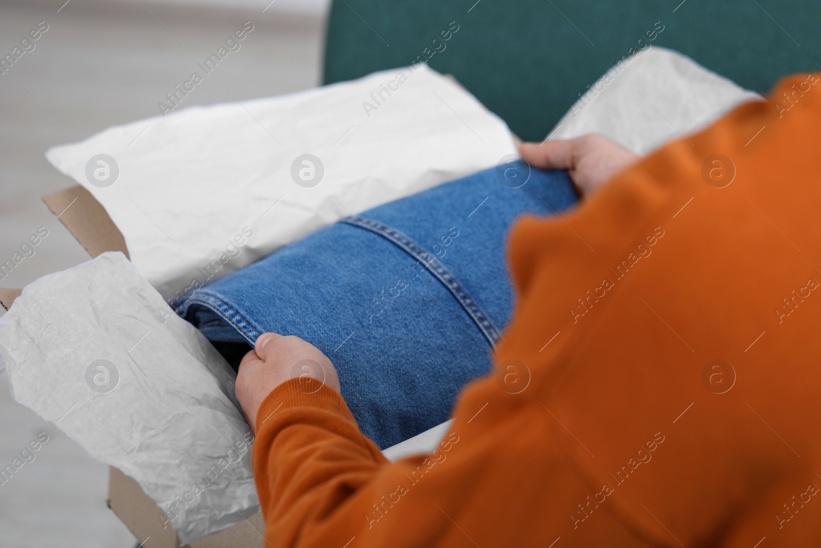 Photo of Man opening parcel with Christmas gift at home, closeup