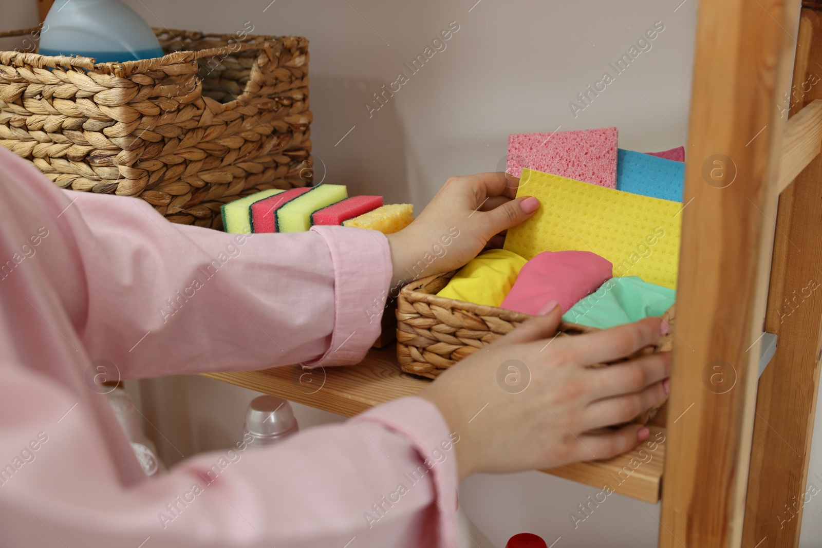 Photo of Woman taking cleaning cloth from basket in laundry room, closeup