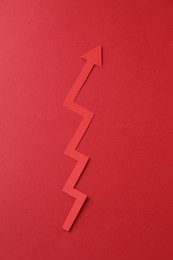 Photo of One zigzag paper arrow on red background, top view