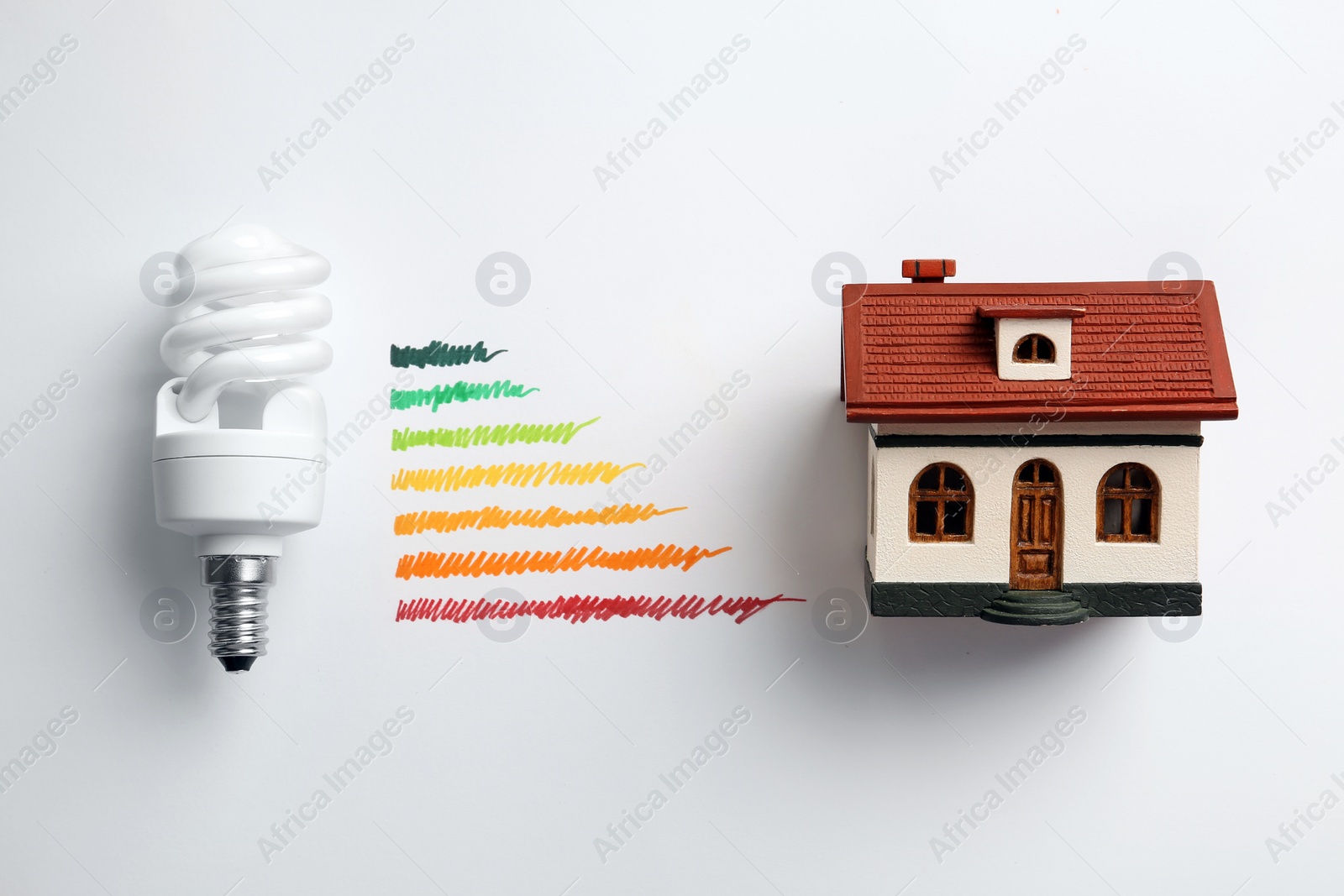 Photo of Flat lay composition with colorful chart, house model and lamp bulb on white background. Energy efficiency concept