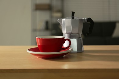 Cup of coffee and moka pot on wooden table indoors