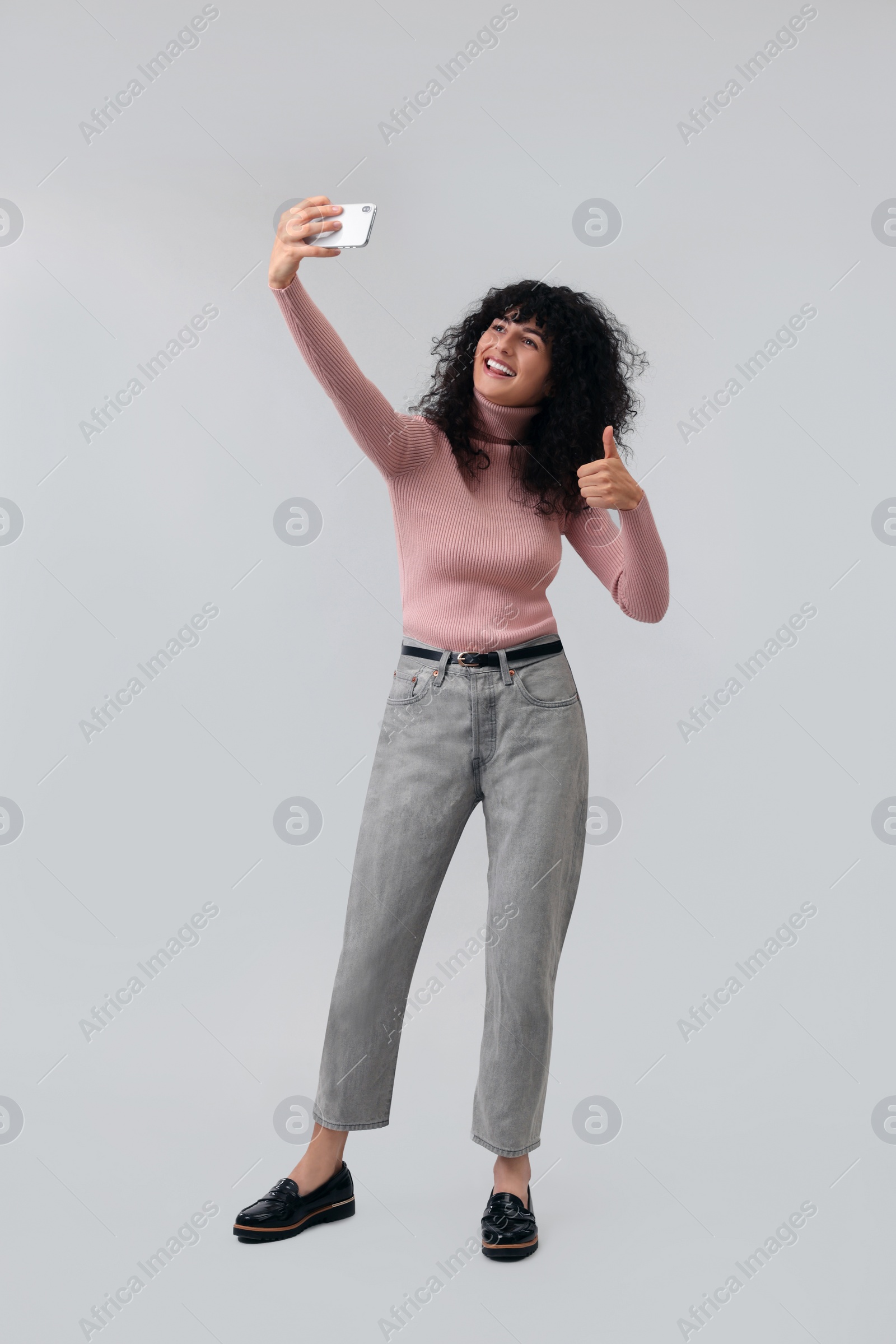 Photo of Beautiful young woman taking selfie on light grey background