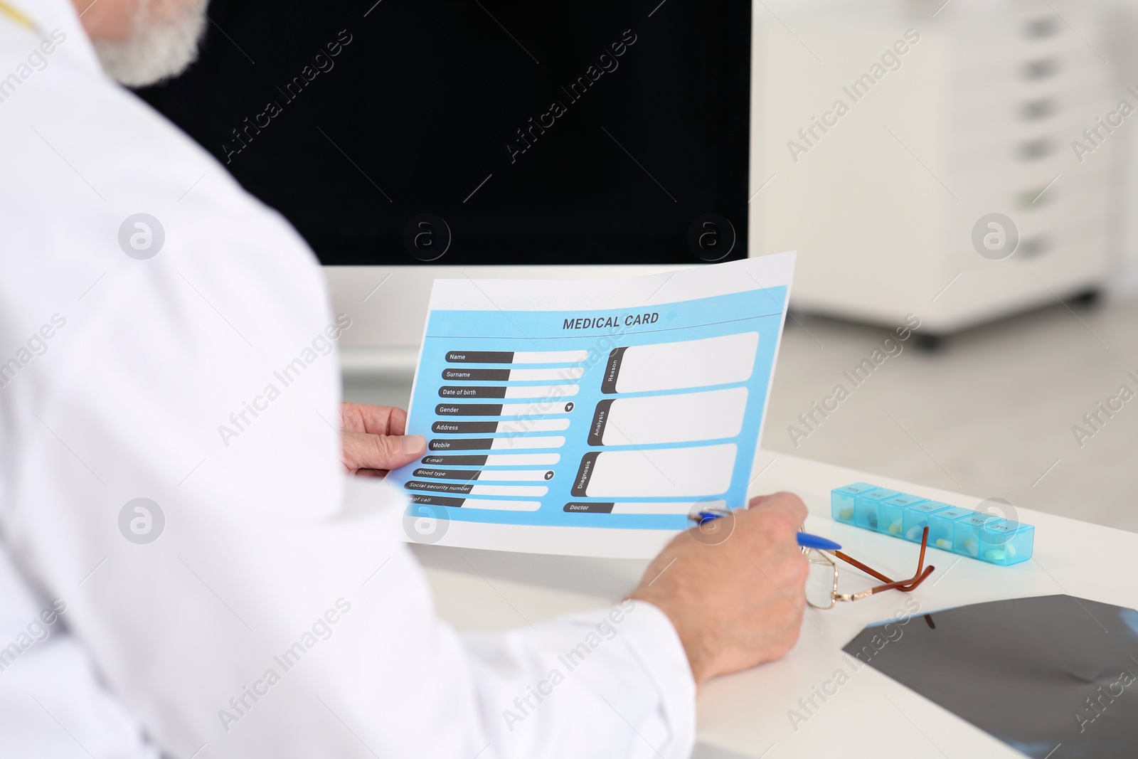 Photo of Doctor with patient's medical card at table in clinic, closeup