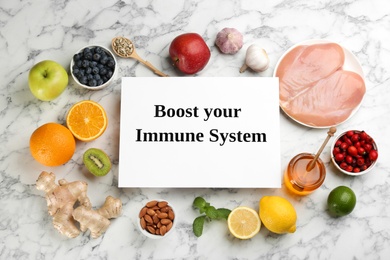 Card with phrase Boost Your immune System and fresh products on light marble table, flat lay