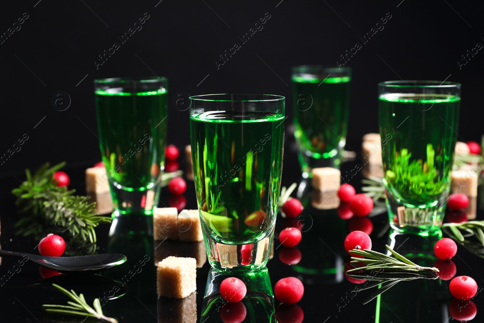 Photo of Absinthe in shot glasses, cranberries, rosemary and brown sugar on mirror table. Alcoholic drink