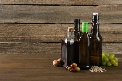 Vegetable fats. Different cooking oils in glass bottles and ingredients on wooden table, space for text