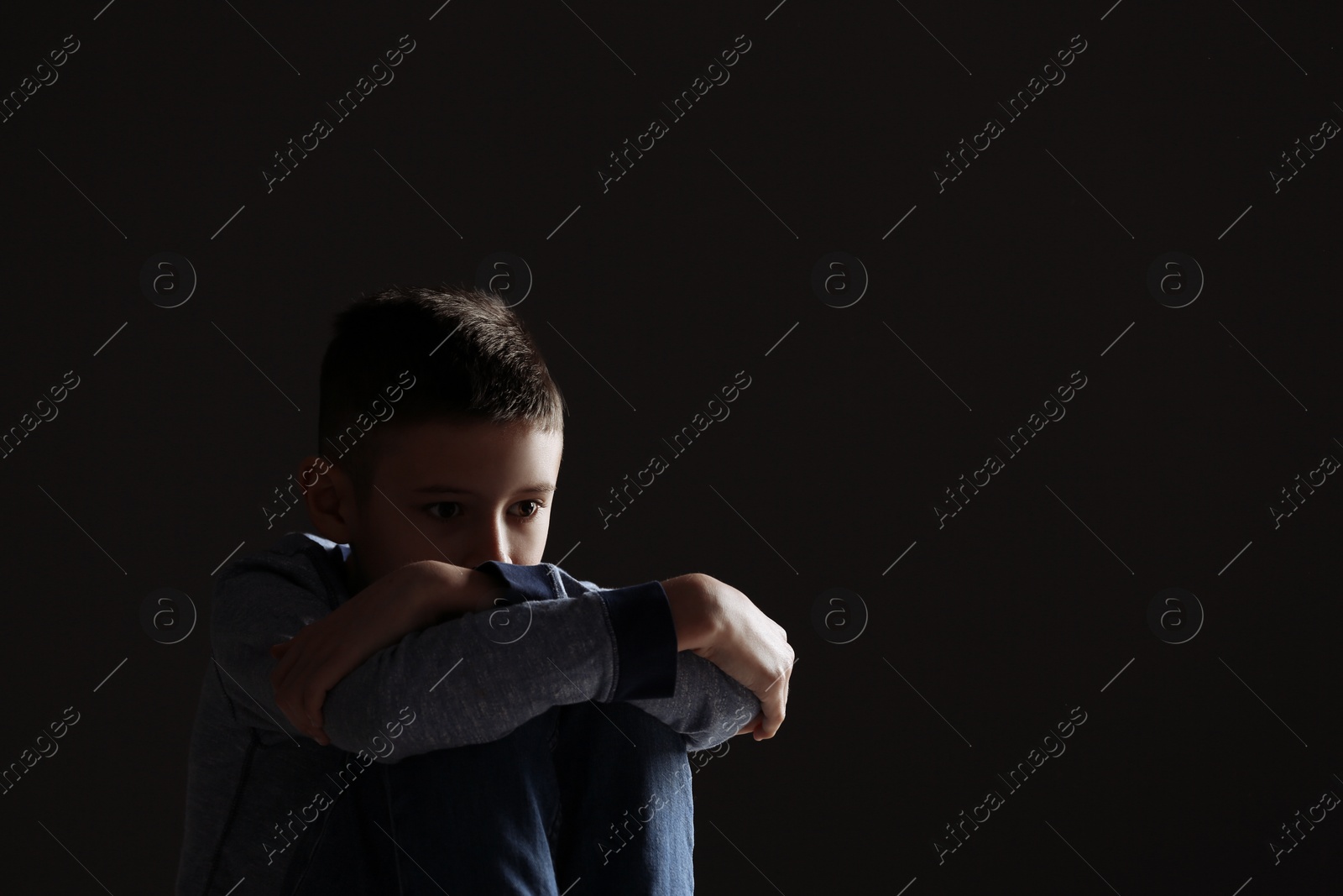 Photo of Upset boy on dark background. Space for text