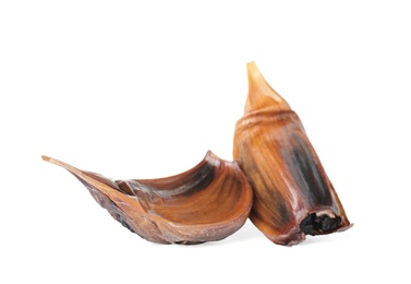 Unpeeled cloves of aged black garlic on white background