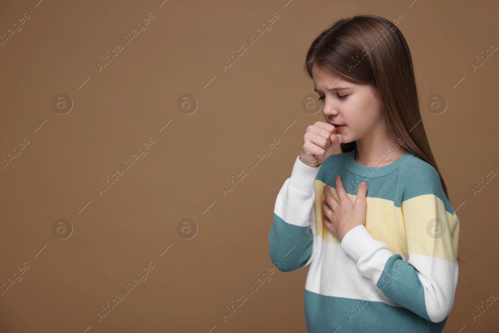 Photo of Sick girl coughing on brown background, space for text