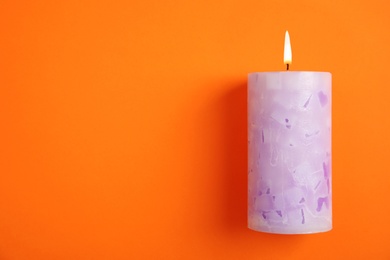 Photo of Alight wax candle and space for text on color background