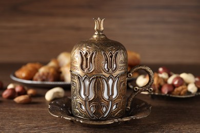 Beautiful cup holder, nuts and baklava dessert on wooden table, closeup