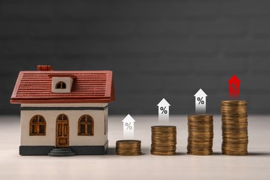 Image of Mortgage rate. Model of house, stacked coins, arrows and percent signs