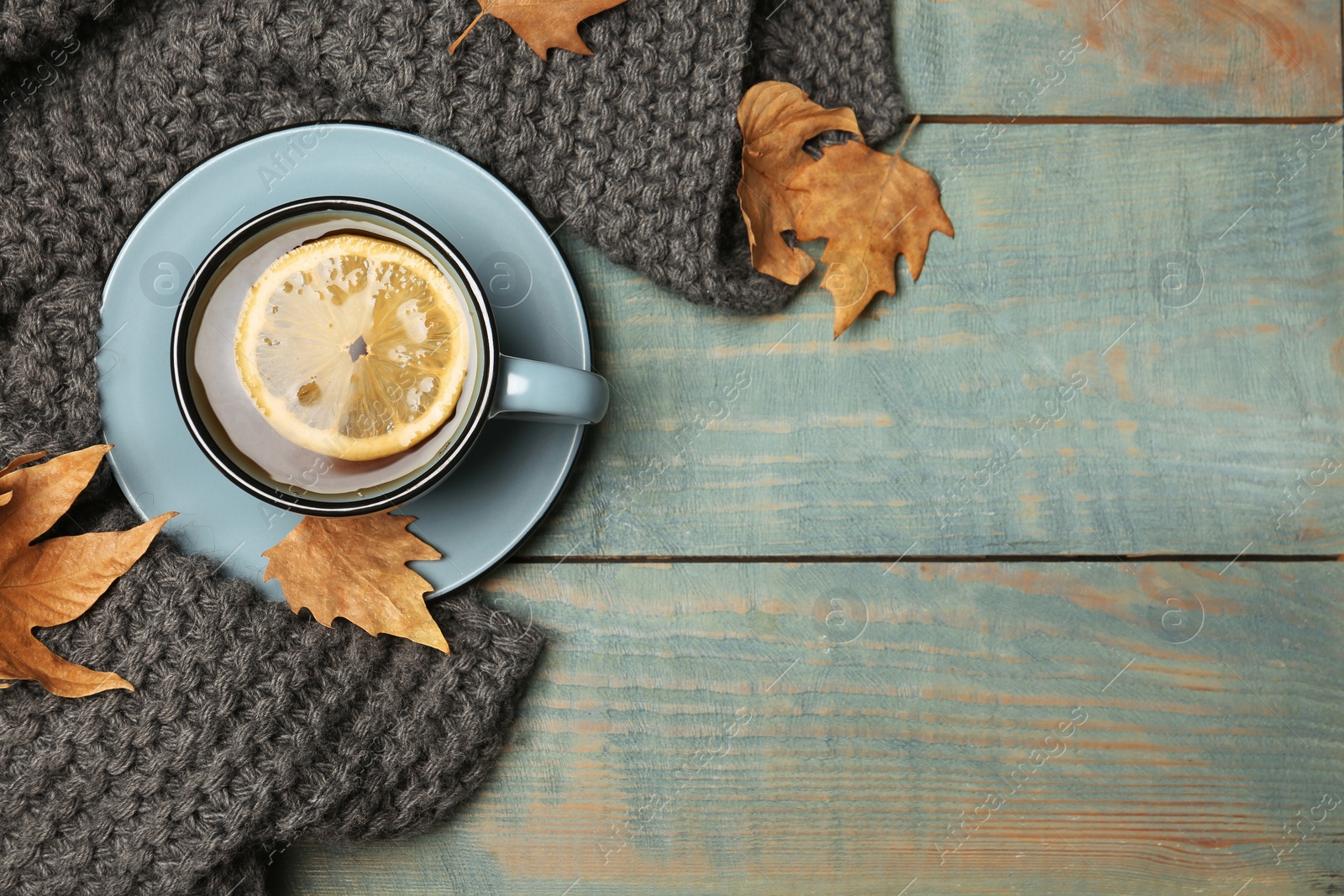 Photo of Flat lay composition with hot cozy drink and autumn leaves on wooden background. Space for text