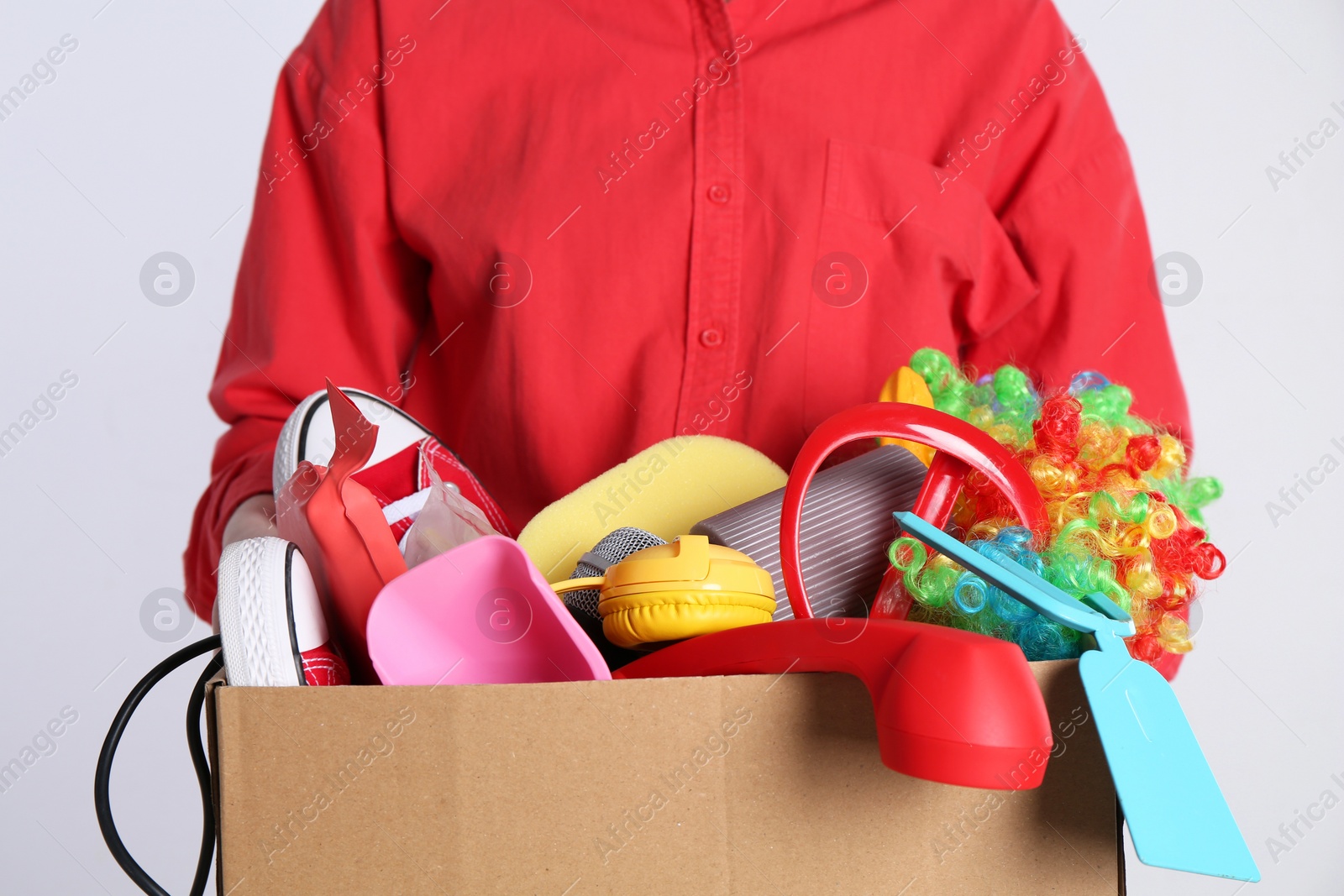 Photo of Woman holding box of unwanted stuff on white background, closeup