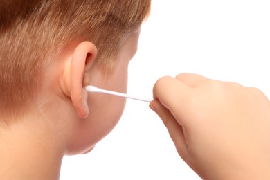Photo of Little boy cleaning ear with cotton swab on white background, closeup