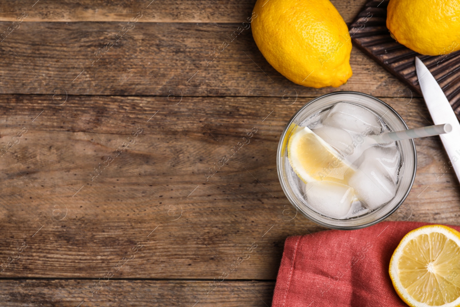 Photo of Soda water with lemon slices and ice cubes on wooden table, flat lay. Space for text