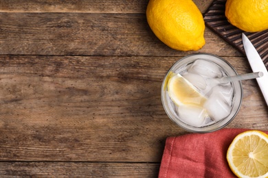 Soda water with lemon slices and ice cubes on wooden table, flat lay. Space for text