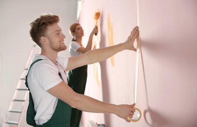 Photo of Professional decorators painting wall indoors. Home repair service