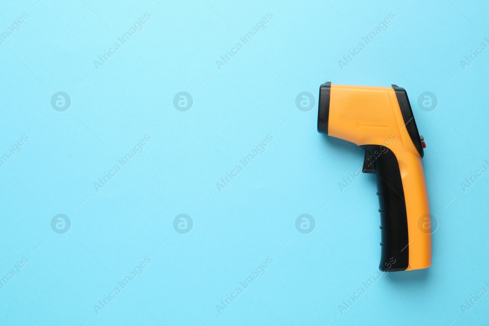 Photo of Infrared thermometer on light blue background, top view with space for text. Checking temperature during Covid-19 pandemic