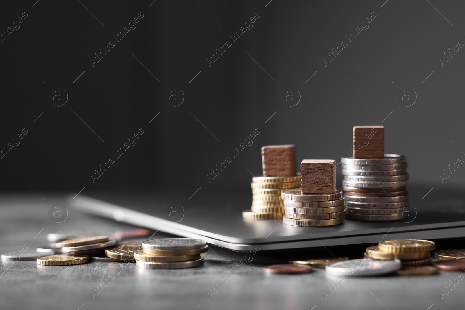 Photo of Taxes. Wooden cubes, laptop and coins at grey table, space for text