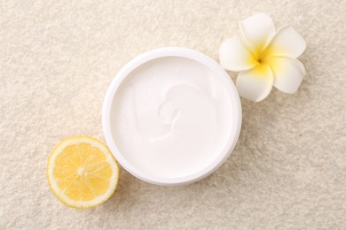 Photo of Flat lay composition with moisturizing cream in open jar and other body care products on light textured table