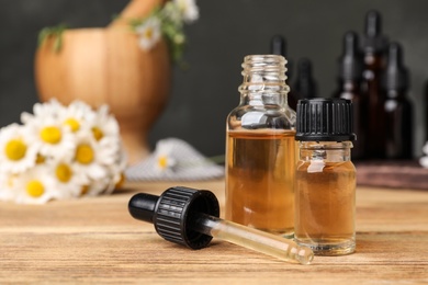 Photo of Composition with bottles of chamomile essential oil on table. Space for text