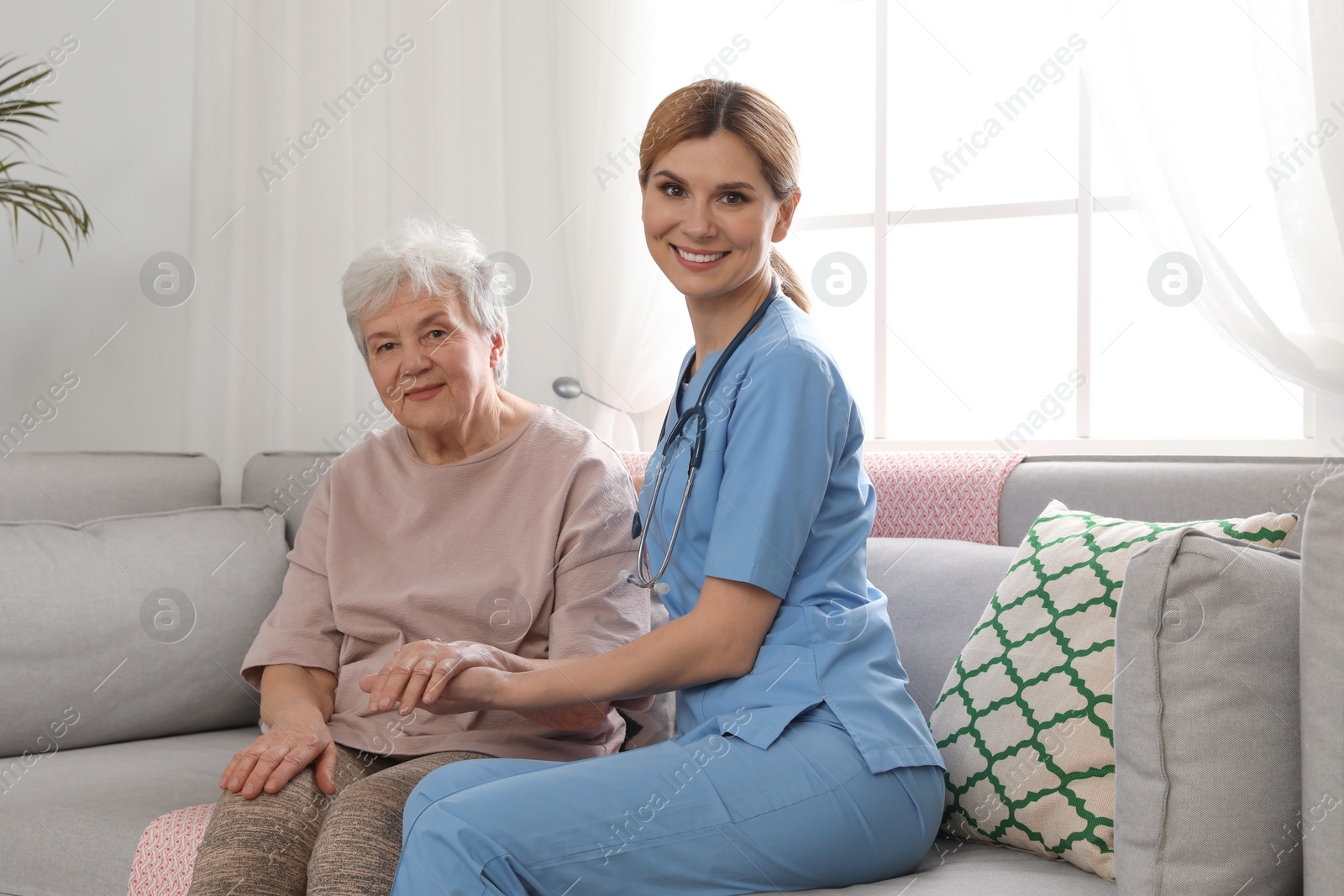 Photo of Nurse with elderly woman indoors. Assisting senior people