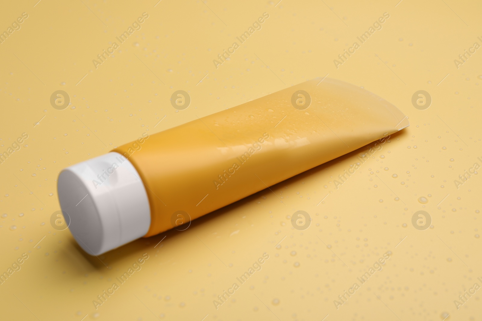 Photo of Wet tube of face cleansing product on pale orange background