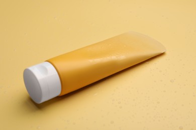 Wet tube of face cleansing product on pale orange background