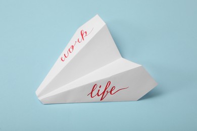 Paper plane with words Work and Life on light blue background. Balance concept