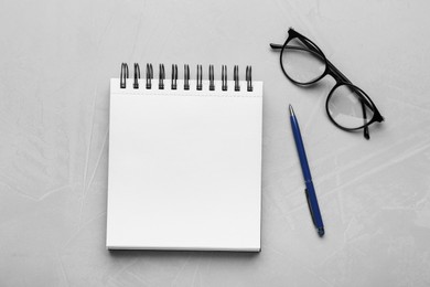 Photo of Notebook, glasses and pen on light textured table, flat lay. Space for text