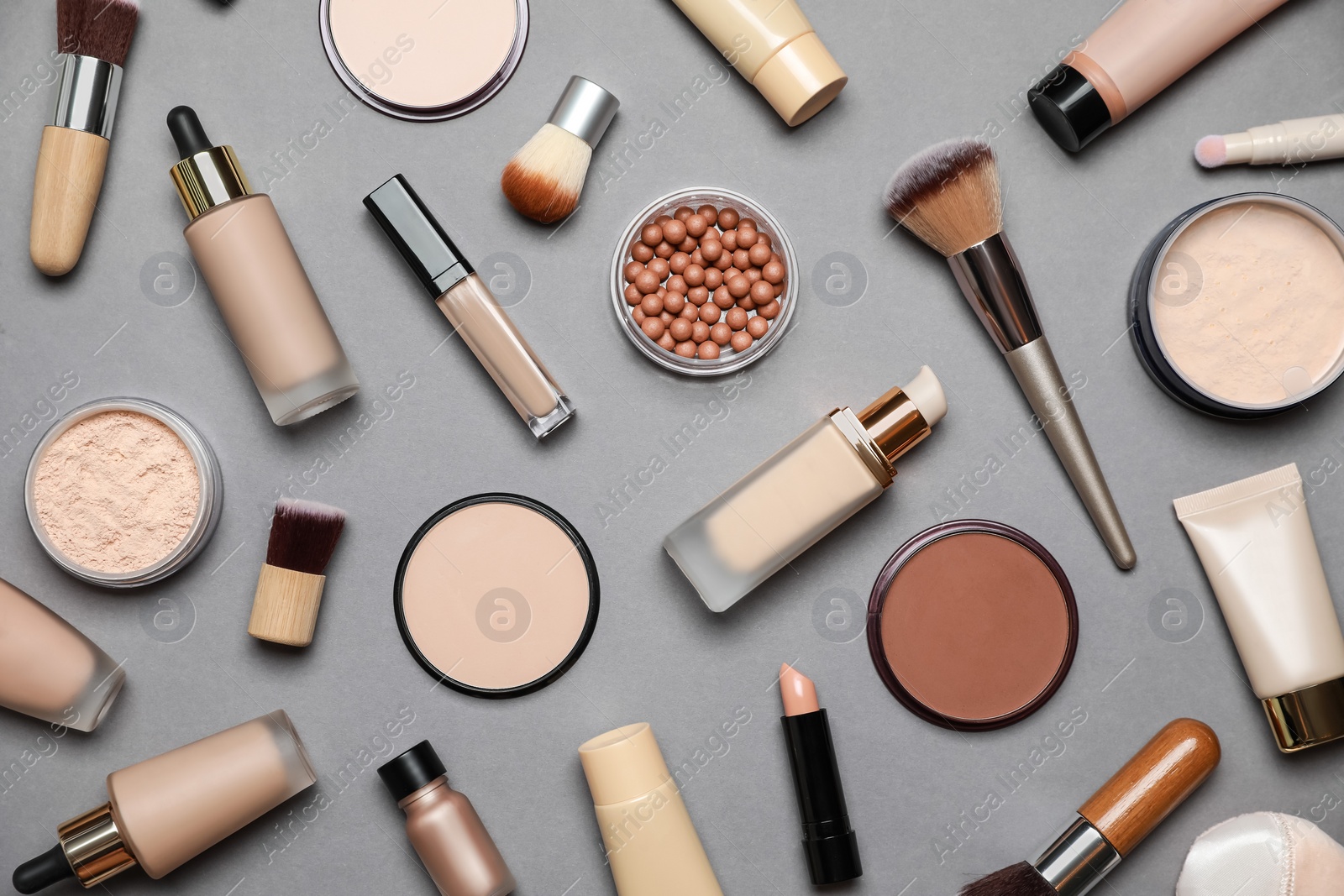 Photo of Face powders and other makeup products on grey background, flat lay