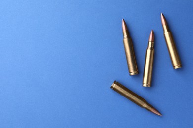 Photo of Bullets on blue background, flat lay. Space for text