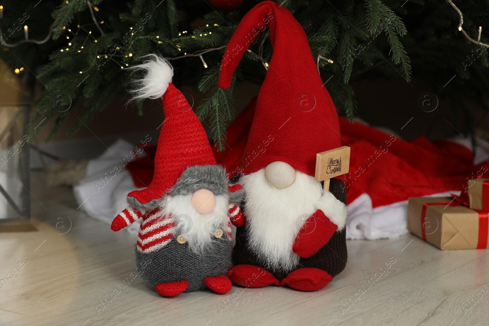 Photo of Cute decorative gnomes on floor near Christmas tree at home