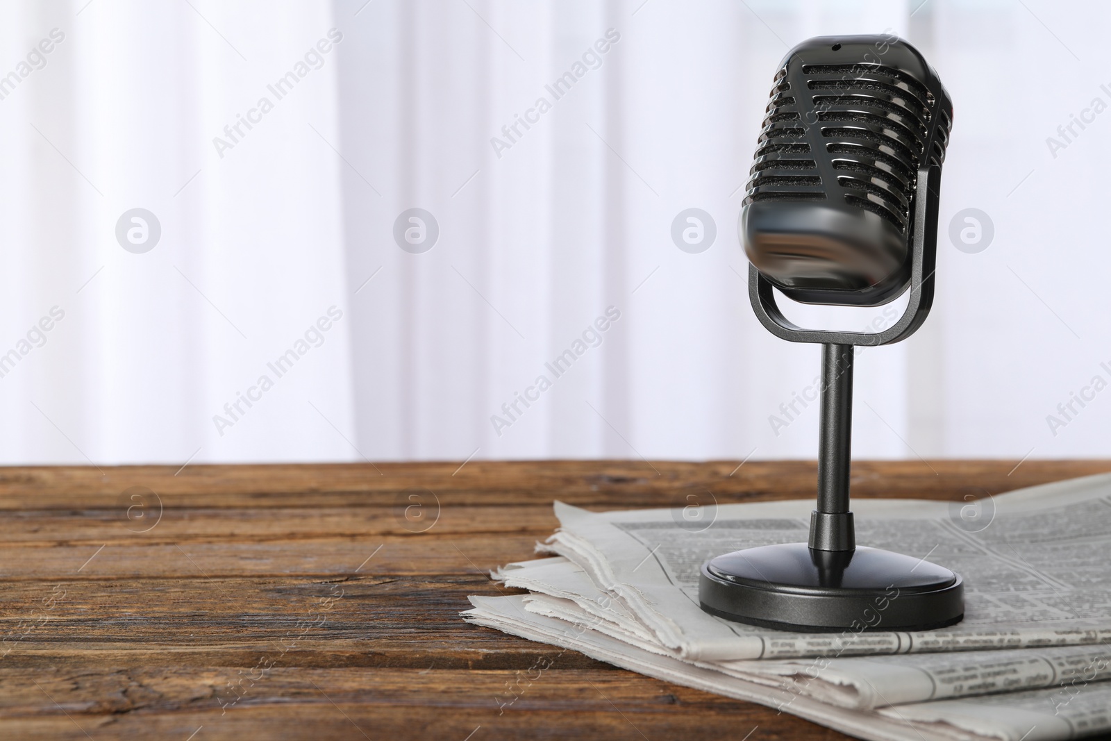 Photo of Newspapers and vintage microphone on wooden table, space for text. Journalist's work