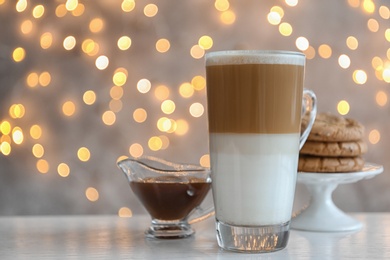 Cup of drink and pastry on table against blurred lights, space for text