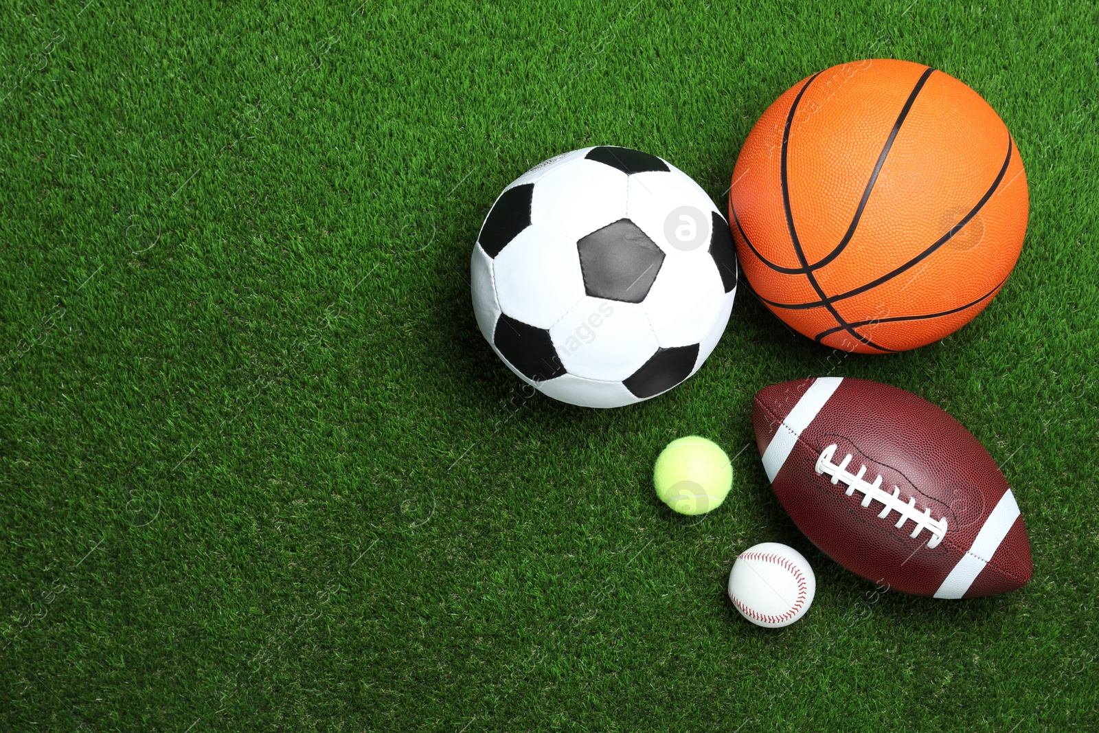 Photo of Set of different sport balls on green grass, flat lay. Space for text