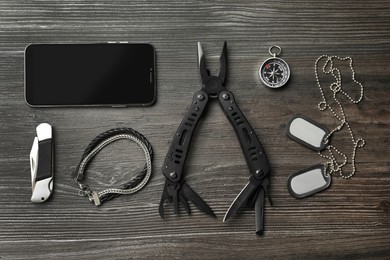 Photo of Flat lay composition with compact portable multitool and accessories on wooden table