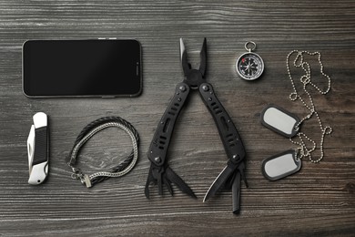 Flat lay composition with compact portable multitool and accessories on wooden table