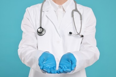 Photo of Doctor with stethoscope holding something on light blue background, closeup