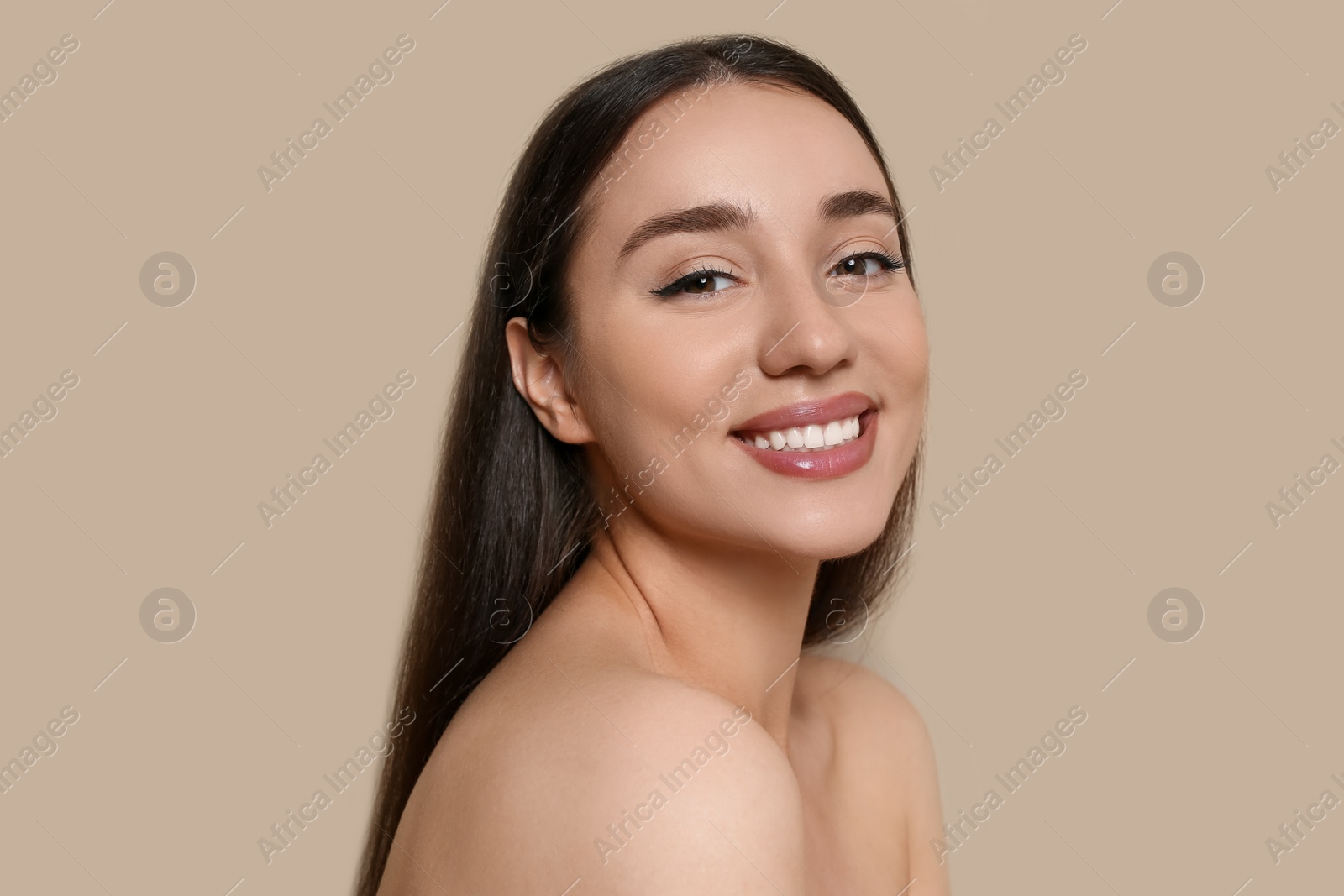 Photo of Portrait of beautiful young woman with elegant makeup on dark beige background