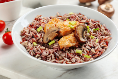 Photo of Tasty brown rice with chicken and mushrooms on table, closeup