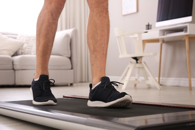 Photo of Man training on walking treadmill at home, closeup
