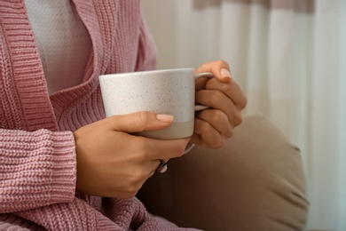 Photo of Woman holding elegant cup at home, closeup