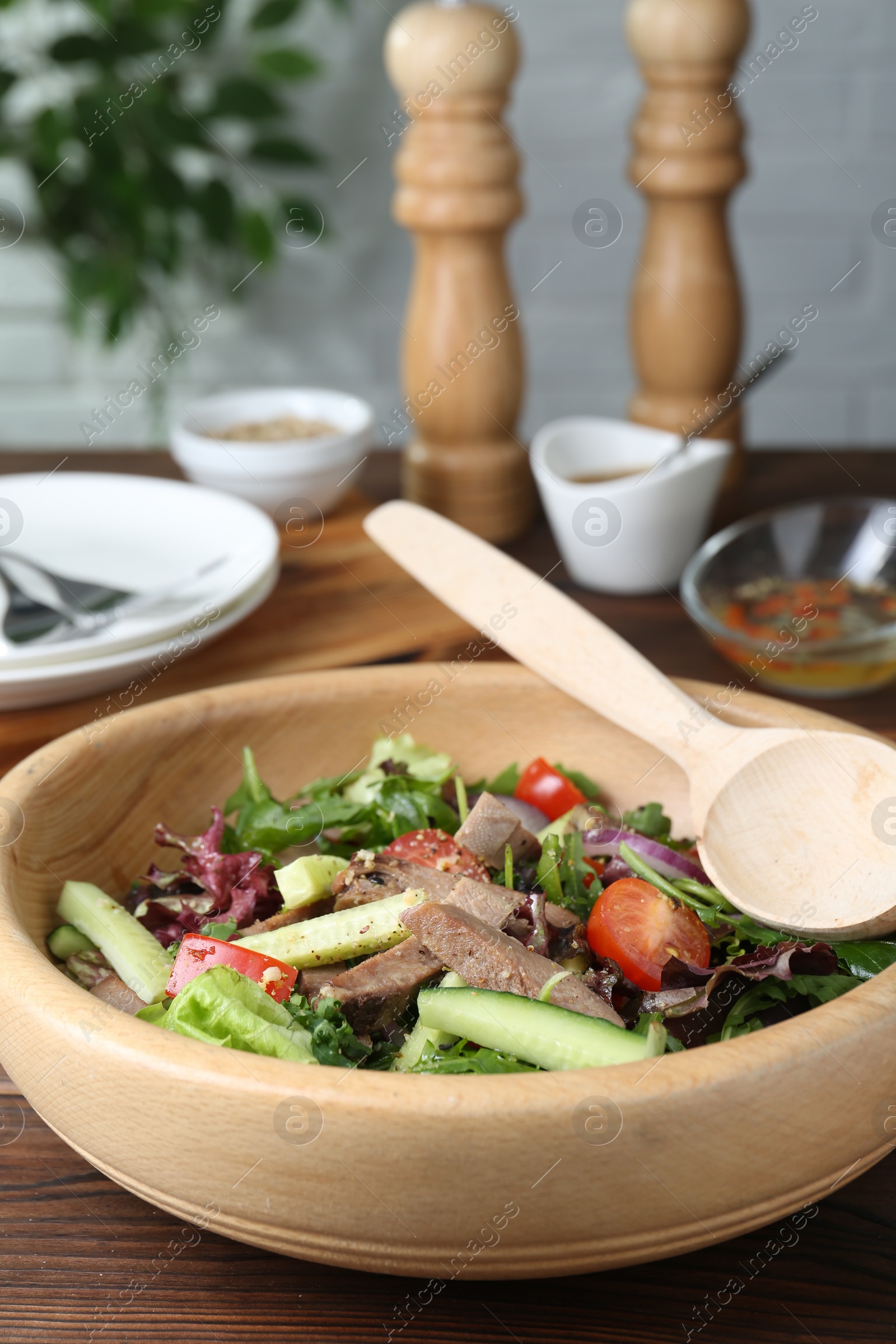 Photo of Delicious salad with beef tongue, vegetables and spoon served on wooden table