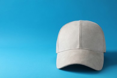 Photo of Stylish beige baseball cap on light blue background. Space for text