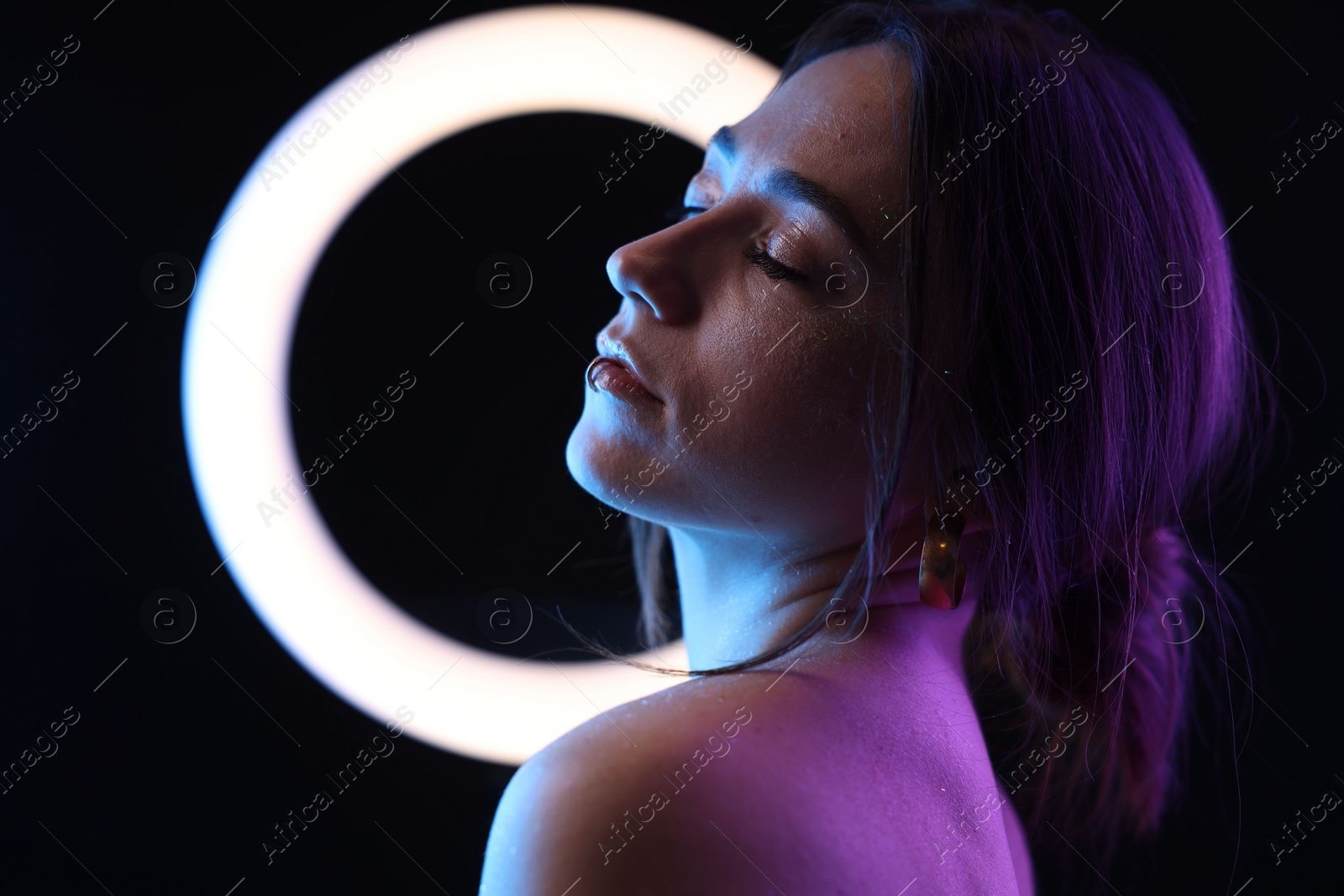 Photo of Beautiful woman and ring lamp on dark background in neon lights