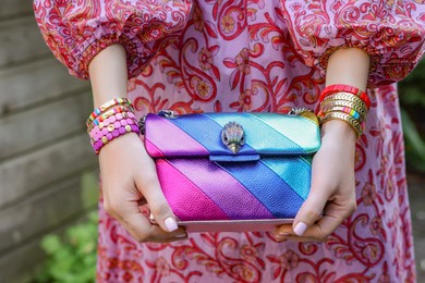 Woman with stylish purse wearing bracelets outdoors, closeup